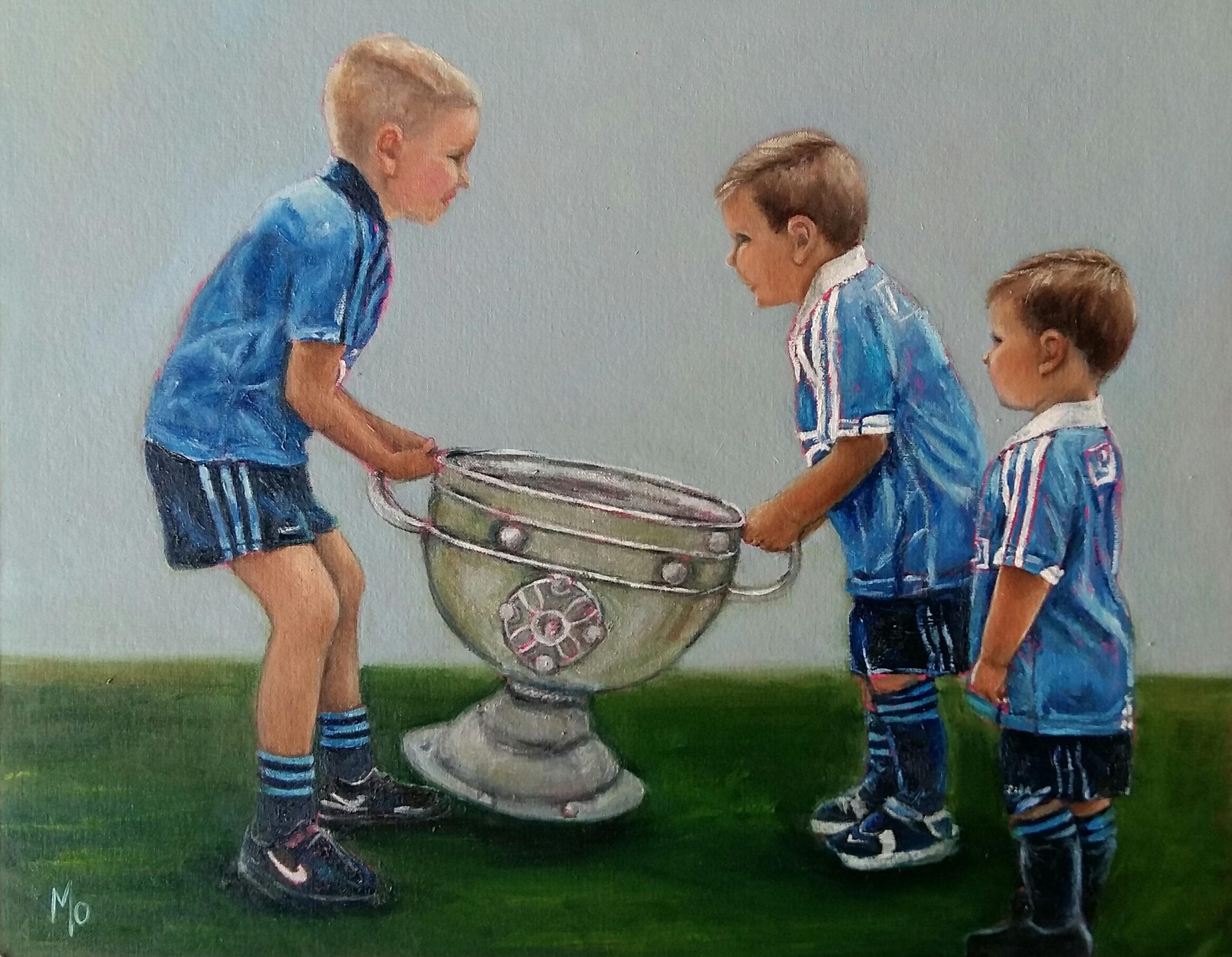 Three boys in Dublin Jerseys lifting the Sam Maguire