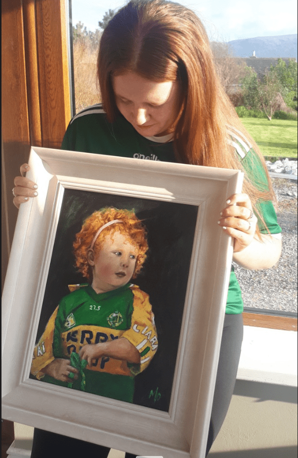 Teenager looking at painting of herself inKerry GAA jersey