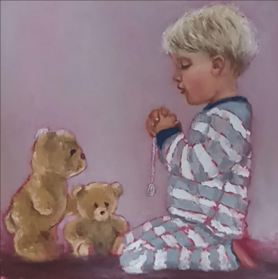 Little boy wearing striped pajamas in prayer pose with two teddybears and a miraculous medal
